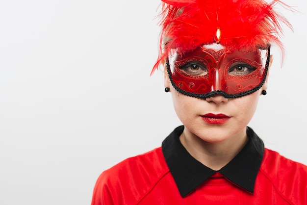 Young woman in mask with red feathers