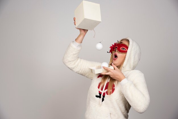 Young woman in masquerade mask getting surprised over bunch of balls.