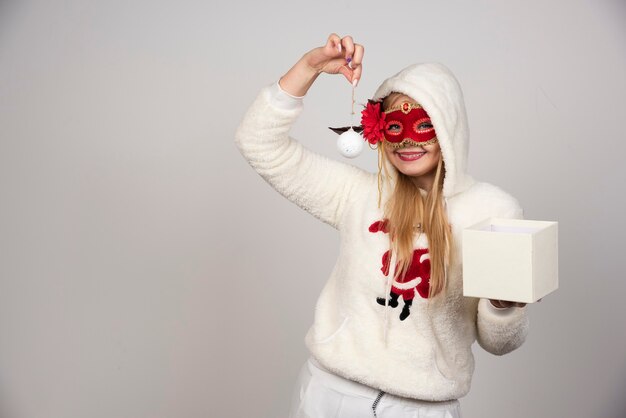 Young woman in masquerade mask holding baubles.