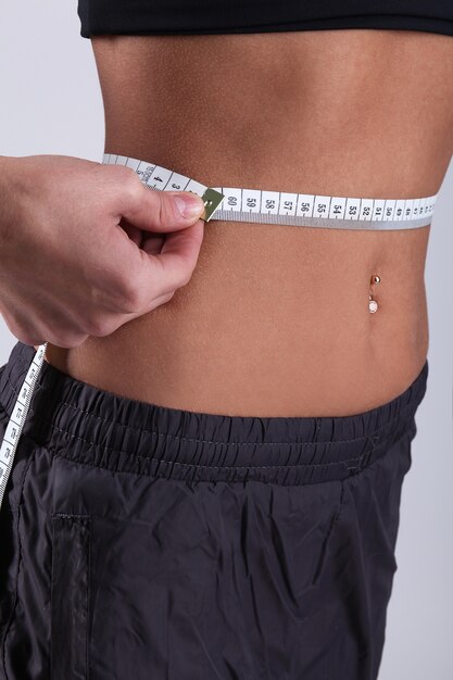 Young woman measuring her waist with tape measure