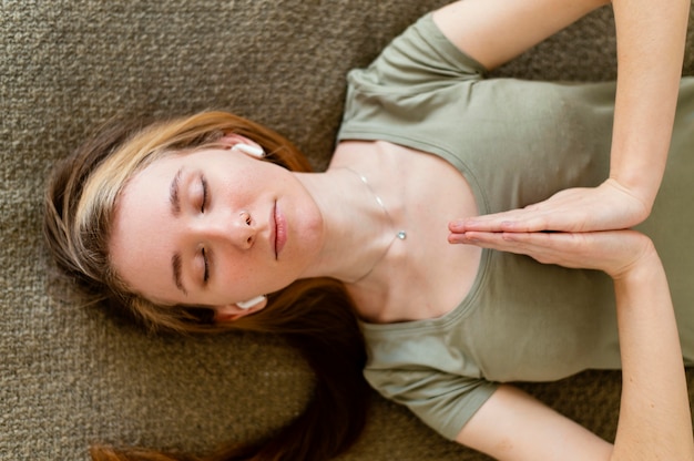 Free photo young woman meditating at home laid on floor