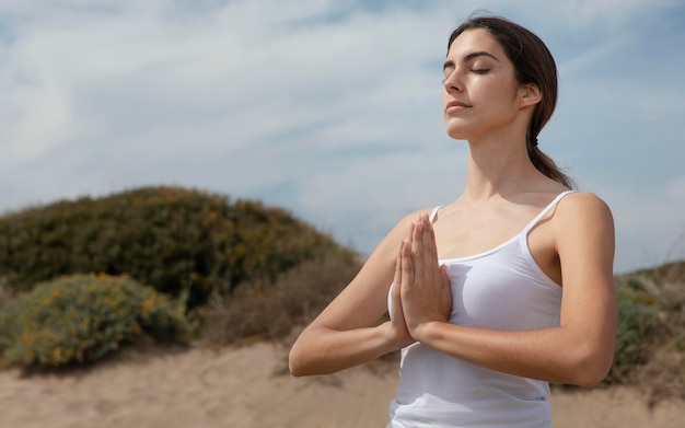 Free photo young woman meditating on sand