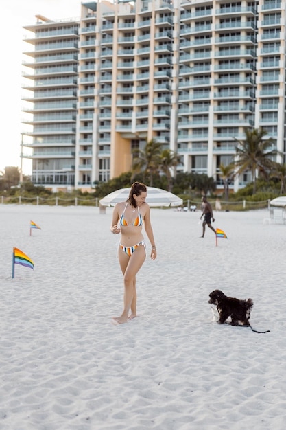 Giovane donna sulla spiaggia di miami con un piccolo cucciolo.