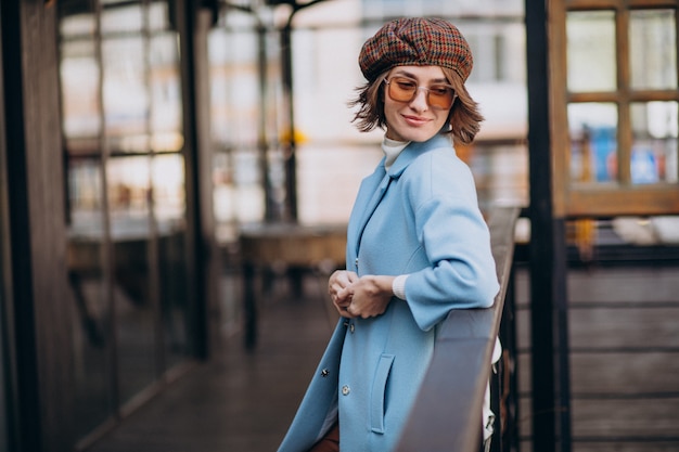 Young woman model in blue coat by the cafe