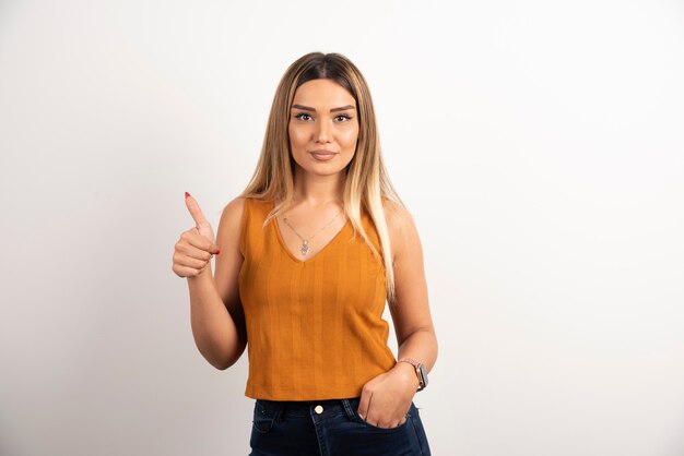 Young woman model in casual clothes showing thumb up and posing