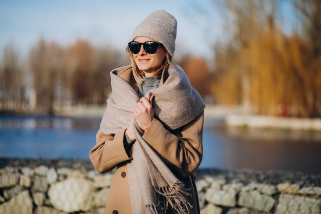 公園の外の暖かいコートに身を包んだ若い女性モデル