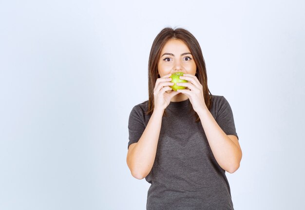 модель молодой женщины ест зеленое яблоко.