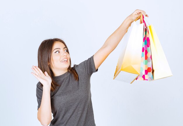 A young woman model holding a lot of shopping bags on white background.