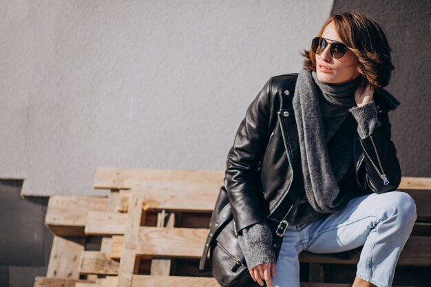 Young woman model in leather jacket outside the street