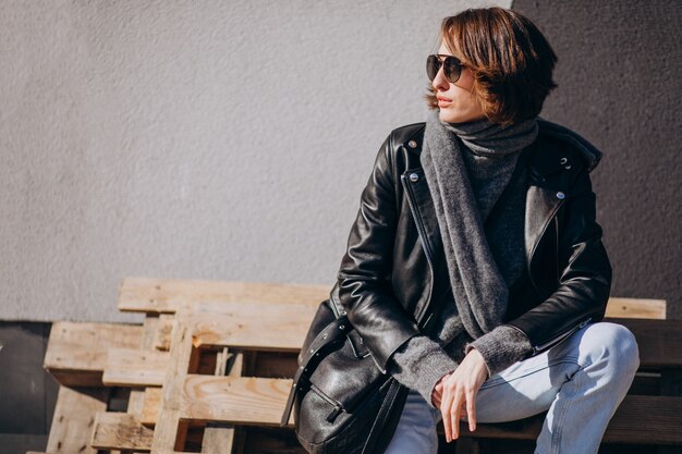 Young woman model in leather jacket outside the street