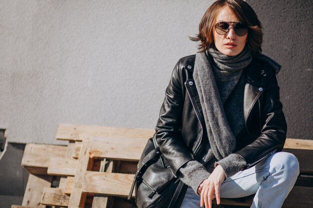 Young woman model in leather jacket outside the street