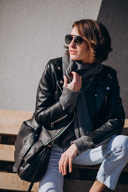 Young woman model in leather jacket outside the street