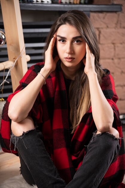 Young woman model posing with checkered plaid near Christmas balls.