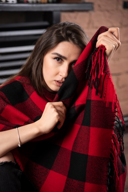 Modello di giovane donna in posa con plaid a scacchi vicino alle palle di natale.