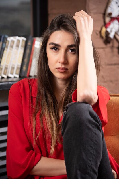 A young woman model in red blouse sitting and posing .