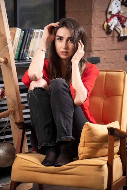 A young woman model in red blouse sitting and posing .