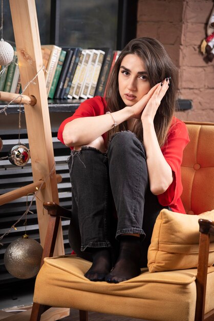 A young woman model in red blouse sitting and posing .