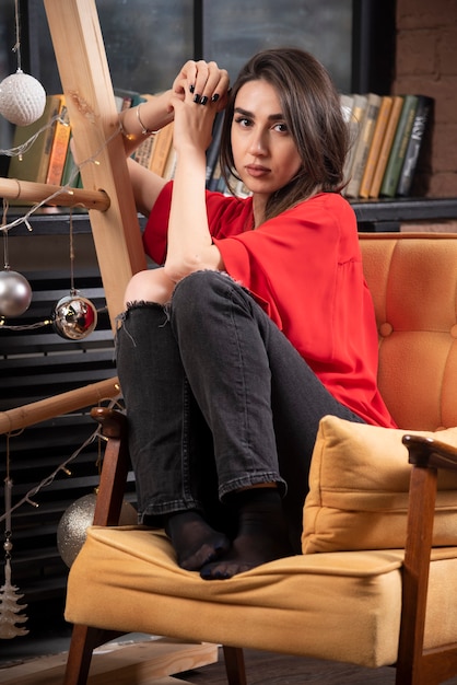 A young woman model in red blouse sitting and posing .