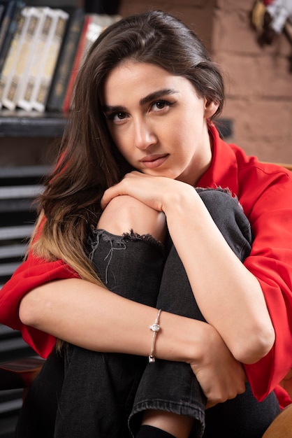 A young woman model in red blouse sitting and posing .