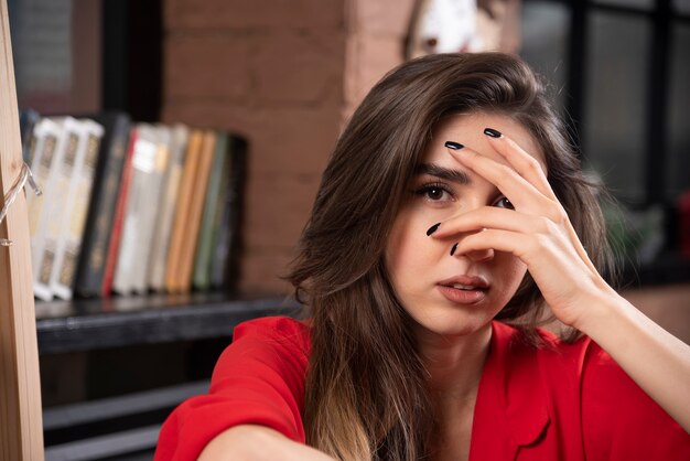 A young woman model in red blouse sitting and posing .