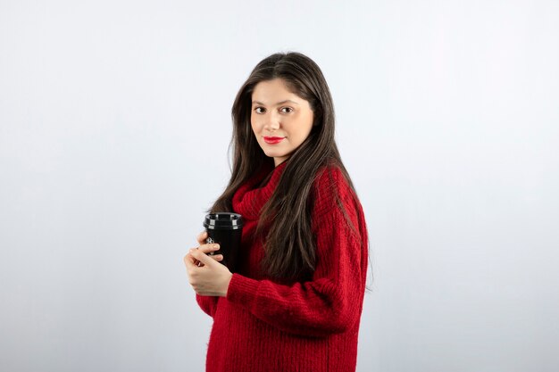 A young woman model in red sweater holding a cup of coffee