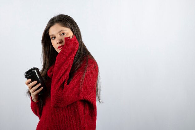커피 한 잔을 들고 빨간 스웨터에 젊은 여자 모델