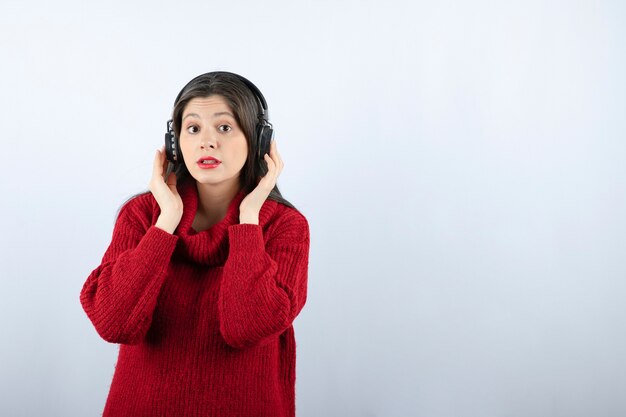 Young woman model in red sweater holding headphones