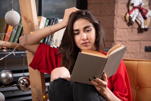 A young woman model sitting and reading a book .