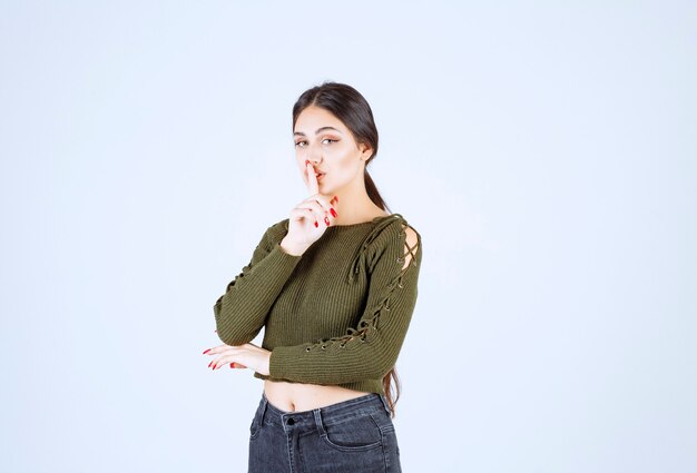 A young woman model standing and doing silent sign.