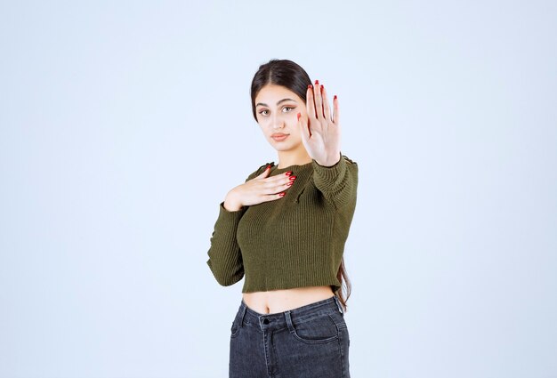 A young woman model standing and doing stop sign .