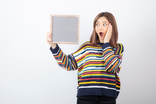 young woman model standing and holding a frame.