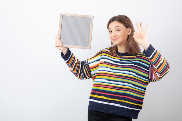 young woman model with a frame showing ok gesture.