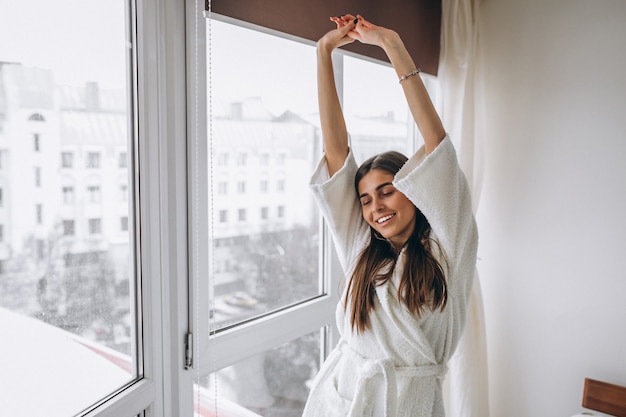 Giovane donna al mattino che si estende dalla finestra