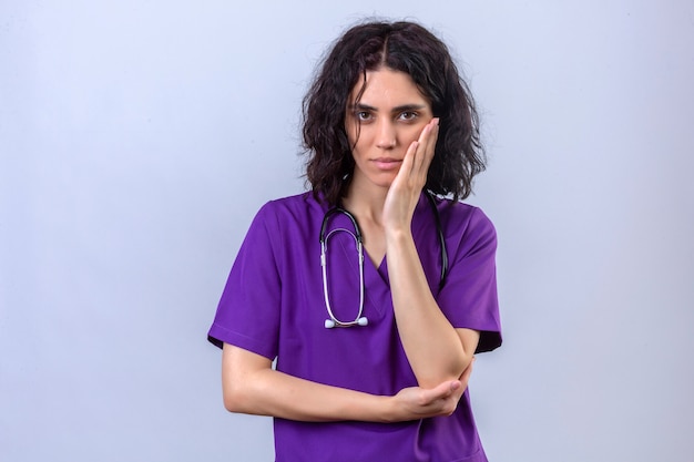 Free photo young woman nurse in medical uniform and with stethoscope touching cheek with hand having toothache