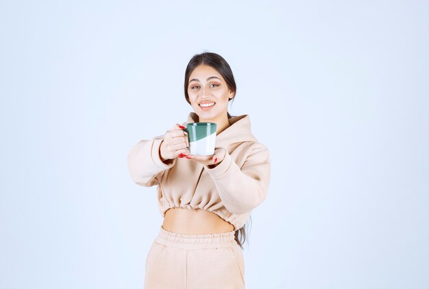 녹색 머그잔에 커피를 제공하는 젊은 여자