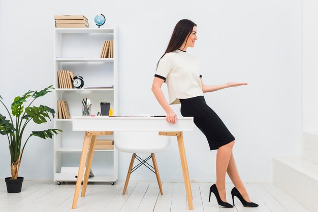 Young woman in office holding something on palm