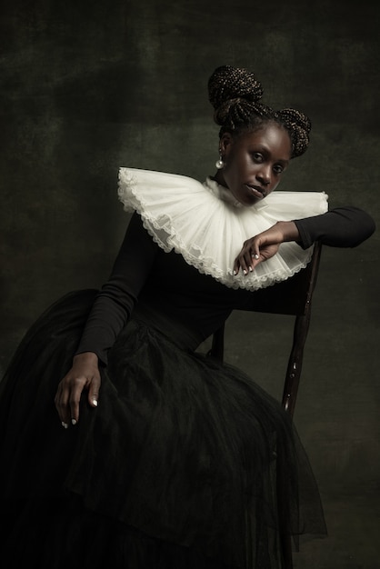 Young woman in old-fashioned dress sits on a chair