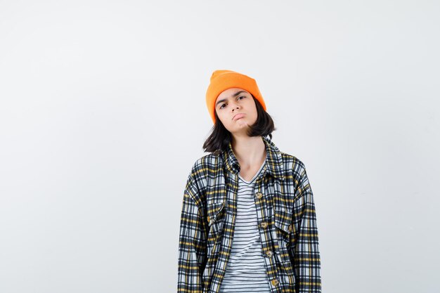 Young woman in orange hat checkered shirt curving lower lips looking aggrieved