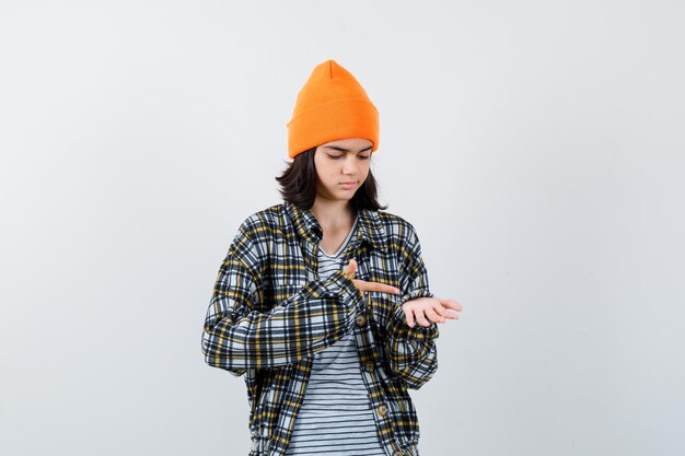 Young woman in orange pointing at her palm and looking pensive