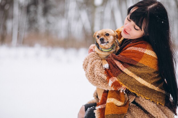 冬に彼女の小さな犬と公園の外の若い女性