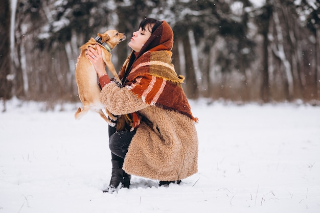 Молодая женщина вне парка с ее маленькой собакой зимой