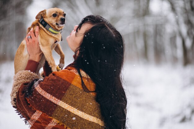 Young woman outside the park with her little dog at winter