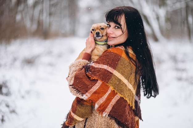 冬に彼女の小さな犬と公園の外の若い女性