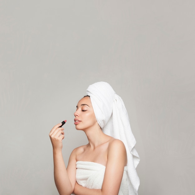 Young woman painting her lips