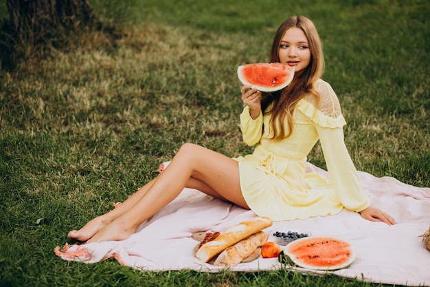 Молодая женщина в парке ест арбуз