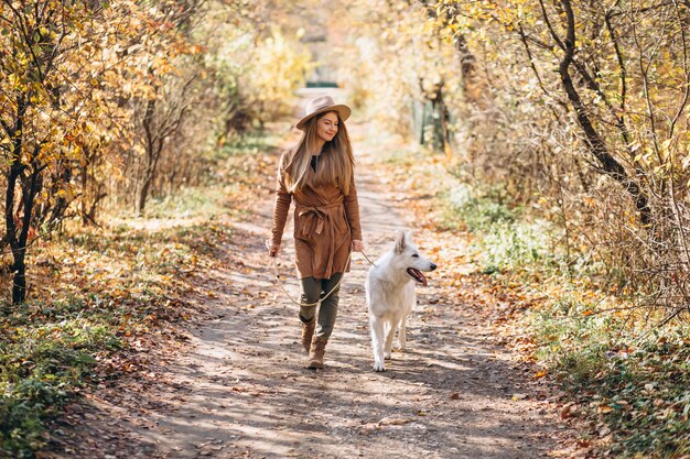 彼女の白い犬と公園の若い女性
