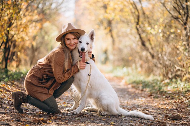 彼女の白い犬と公園の若い女性