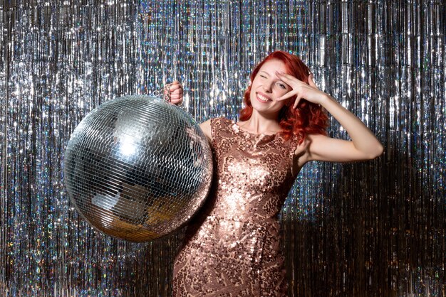 young woman in party with disco ball on bright curtains