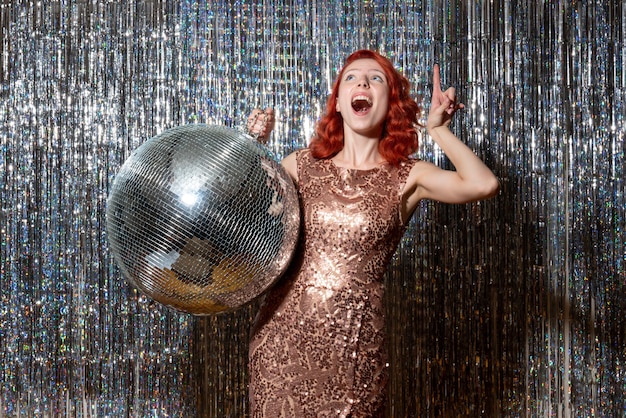 молодая женщина в вечеринке с диско-шаром на ярких шторах