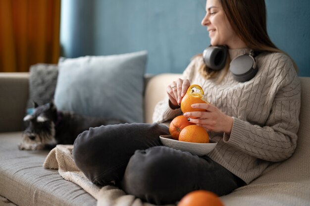 Free photo young woman peeling an orange on the sofa